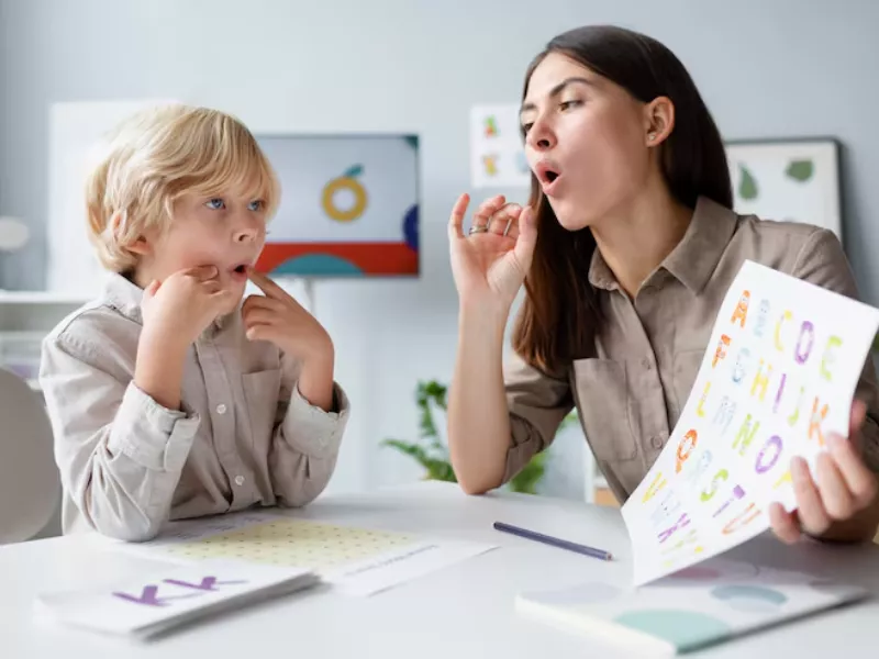 A speech-language pathologist assists a young boy with articulation exercises for a Language Disorder or Language Difference