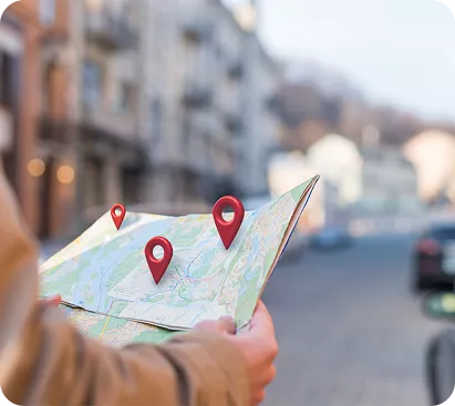  A person holding an open paper map with red location pins, overlooking a scenic landscape, representing Australian translation services locations.